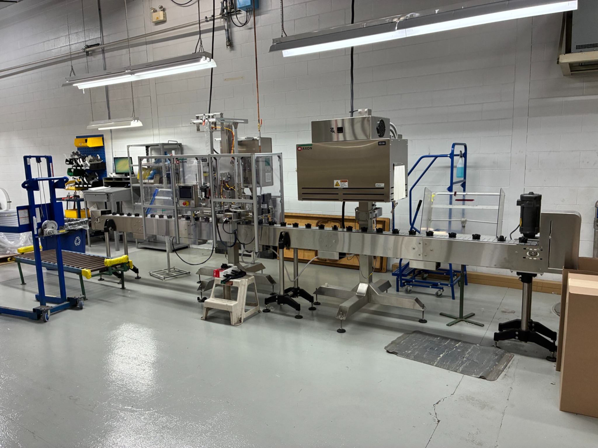 AXON sleeve labeller, tamper band system and conveyor line